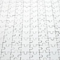 Close up of a white jigsaw puzzle in assembled state in perspective. Many components of a large whole mosaic are united photo