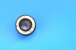 One photographic lense lie on a bright blue background. Space for text photo