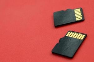 Two small micro SD memory cards lie on a red background. A small and compact data and information store photo