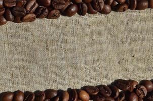 Texture of a gray canvas made of old and coarse burlap with coffee beans on it photo