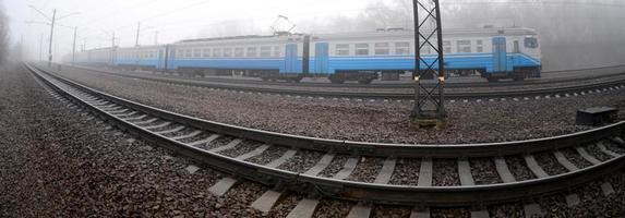 The Ukrainian suburban train rushes along the railway in a misty morning. Fisheye photo with increased distortion