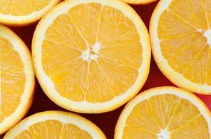 Top view of a several orange fruit slices on bright background in red color. A saturated citrus texture image photo
