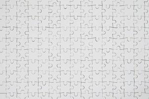 Close up texture of a white jigsaw puzzle in assembled condition. Top view. Many components of a large whole mosaic are united photo