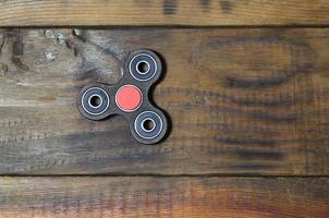 A rare handmade wooden fidget spinner lies on a brown wooden background surface. Trendy stress relieving toy photo