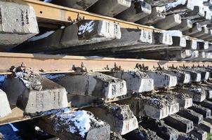 A lot of old rails and sleepers are stacked in a railway warehouse in winter. The concept of renewing a worn-out railway track photo