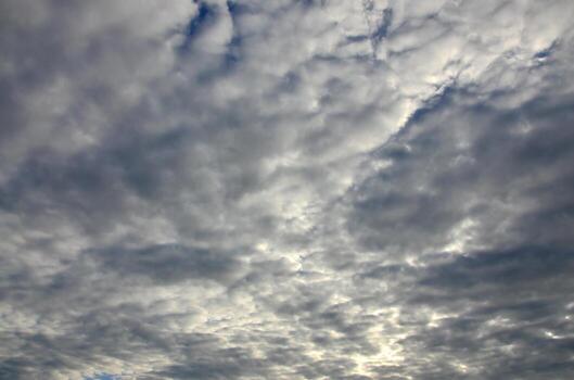 A blue cloudy sky with many small clouds blocking the sun photo