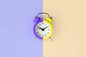 A small alarm clock is located between the violet and cream background areas photo