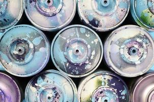 A few used spray cans with blue paint drips lie on texture background of fashion pastel blue color paper photo