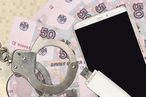50 russian rubles bills and smartphone with police handcuffs. Concept of hackers phishing attacks, illegal scam or malware soft distribution photo