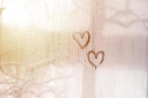 dos corazones pintados en un vidrio empañado en invierno foto