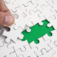 The human hand fills the last missing elements of the surface from the jigsaw puzzle. The concept of the completion of the initiated cases photo