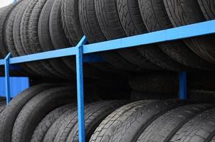 Rack with variety of car tires in automobile store. Many black tires. Tire stack background. Selective focus photo