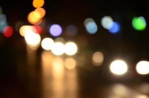 escena nocturna borrosa de tráfico en la carretera. imagen desenfocada de coches que viajan con faros luminosos. arte bokeh foto