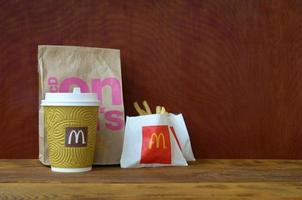 KHARKOV, UKRAINE - DECEMBER 9, 2020 McDonald's take away paper bag and junk food on wooden table photo