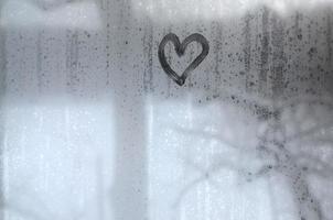 The heart is painted on the misted glass in the winter photo