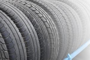 Rack with variety of car tires in automobile store. Many black tires. Tire stack background. Selective focus photo