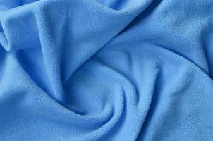 The blanket of furry blue fleece fabric. A background of light blue soft plush fleece material with a lot of relief folds photo