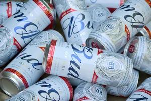 KHARKOV, UKRAINE - DECEMBER 9, 2020 Many Cans of Budweiser Lager Alcohol Beer lies on camo surface. Budweiser is Brand from Anheuser-Busch Inbev most popular in America photo