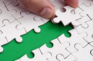 The human hand paves the way to the surface of the jigsaw puzzle, forming a green space. The concept of overcoming the difficulties on the way to success photo