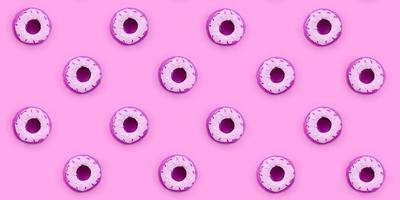 Many small plastic donuts lies on a pastel colorful background. Flat lay minimal pattern. Top view photo