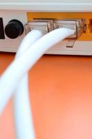 The Internet cable plugs are connected to the Internet router, which lies on a bright orange background. Items required for Internet connection photo