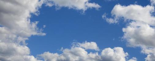 The blue sky with a lot of white clouds of different sizes, forming a frame around the cloudless area photo