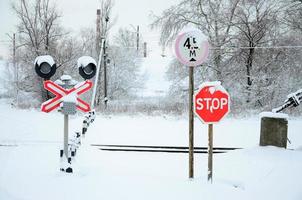 deténgase. la señal de carretera roja se encuentra en la autopista que cruza la línea ferroviaria en la temporada de invierno foto