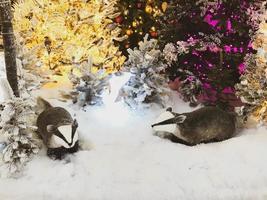 two funny raccoons are sitting under a tree on new year's eve. decorations for the shopping center and shop windows. cute decoration for buyers. cute handmade decoration photo