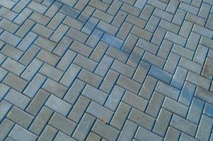 asphalt stones lie on the road in the shape of a herringbone. rectangular bricks for laying out the road on the street. sidewalk paths in the city of gray color with rubbish on the surface photo