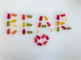 letras de oso hechas de hermosos dulces deliciosos caramelos gomosos de frutas jugosas masticables multicolores osos sobre un fondo blanco foto