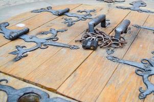 Texture of old ancient medieval antique sturdy wooden natural thick door with rivets and nails patterns and locks made of wooden planks. The background photo