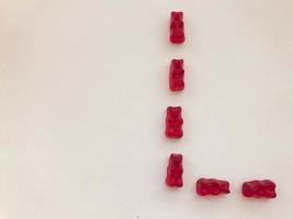 creativa letra comestible l hecha de ositos de goma. carta elaborada a base de caramelos rojos, gelatinosos y sabrosos. inscripción creativa, imagen inusual del alfabeto. alfabeto comestible foto