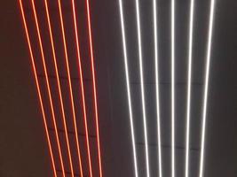 Blurred, no focused, abstract festive vertical background with red, orange and white neon led stripes on a black background, photography for creative workspace for design photo