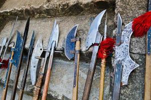 las antiguas armas frías medievales, hachas, olibards, cuchillos, espadas con mangos de madera lamen en los escalones de piedra del castillo foto