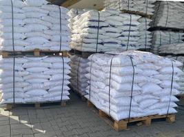 White polypropylene large bags with building materials or bulk materials lie on top of each other on wooden pallets in an industrial warehouse photo