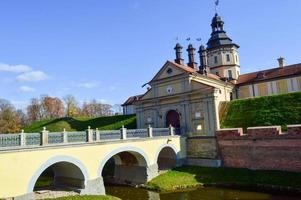 Old, ancient medieval castle with spiers and towers, walls of stone and brick surrounded by a protective moat with water in the center of Europe. Baroque style architecture photo