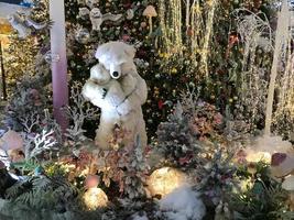 Lonely Teddy Bear Sitting nearby Window in House on Christmas Night, Xmas Tree with Lights as outside view photo