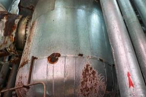 The large tank heat exchanger in insulation insulated by rust corrosion with holes is old at an industrial chemical oil refinery petrochemical plant photo