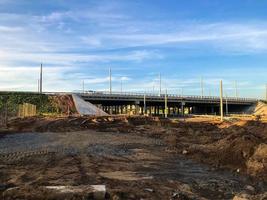 lugar debajo del puente, cruce de carreteras. charco de lodo, arena con agua, estructuras de madera. cerca hay montones de arena, arena con escombros y piedras. construcción de una intersección foto