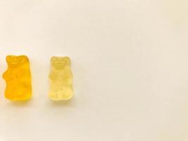 gummy bears of bright colors on a blue matte background. white and yellow transparent bear. delicious appetizing candies of an unusual shape photo