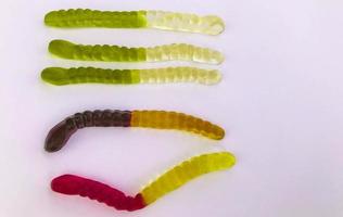 gummy worms lie on a white matte background. bright, mouth-watering gelatinous worms of different colors. worms are stacked in rows, according to colors, from light to dark photo