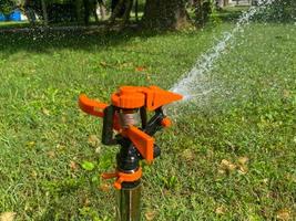 Automatic green grass sprinkler, water sprayer for watering lawn plants photo