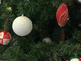 bolas multicolores hermosas y brillantes, juguetes, cajas de regalo, decoraciones en el árbol verde de navidad con agujas y ramas para el nuevo año. fondo, textura foto