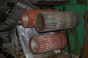 Large metal rollers rolls with teeth of the gears of the production line, a conveyor belt in the workshop at an industrial chemical petrochemical machine-building refinery with equipment machines photo