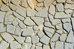 The texture of the stone road, pavement, walls of large gray old medieval round strong stones, cobblestones. The background photo