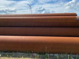 Lots of large diameter industrial iron rusty pipes with corrosion ready for installation plumbing for oil refinery petrochemical plant equipment at construction site photo
