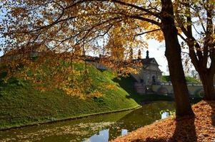 Old, ancient medieval castle with spiers and towers, walls of stone and brick surrounded by a protective moat with water in the center of Europe. Baroque style architecture photo