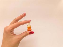 dulces de mermelada. una chica con manicura roja sostiene dulces en forma de botella con limonada. caramelo dulce en forma de botella de cola, caramelo gomoso foto