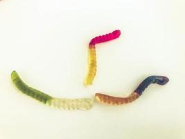 gummy worms of different colors lie on a white matte background. gelatinous sweetness. worms in the shape of a ship. handmade dessert. appetizing delicious candy photo