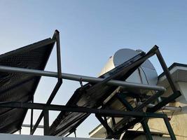 vista del techo de un edificio en un cálido país tropical con paneles solares y un tanque de agua en el techo. tecnologías ecológicas de bajo consumo foto